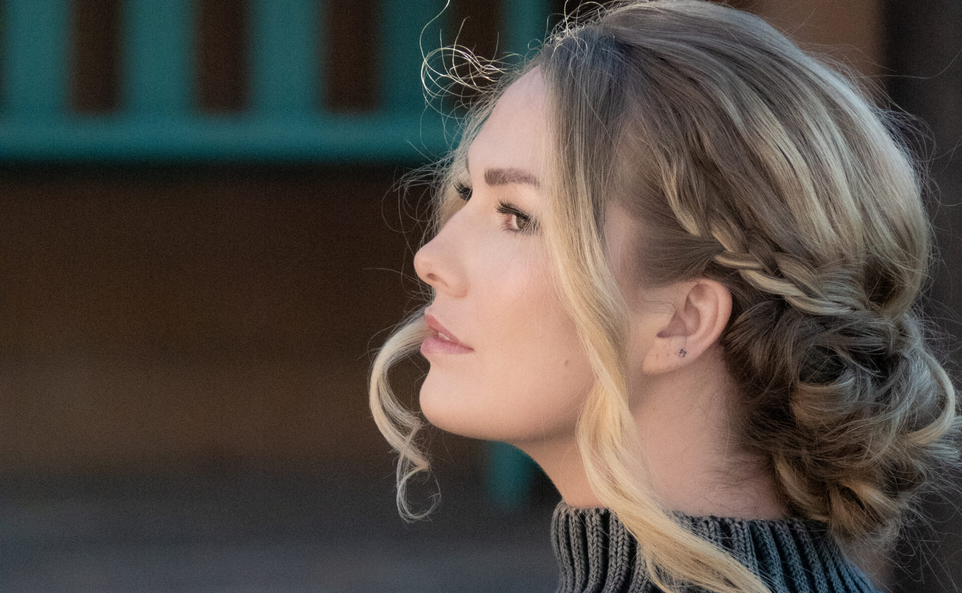 Woman with a side-swept braid in wavy blonde hair.