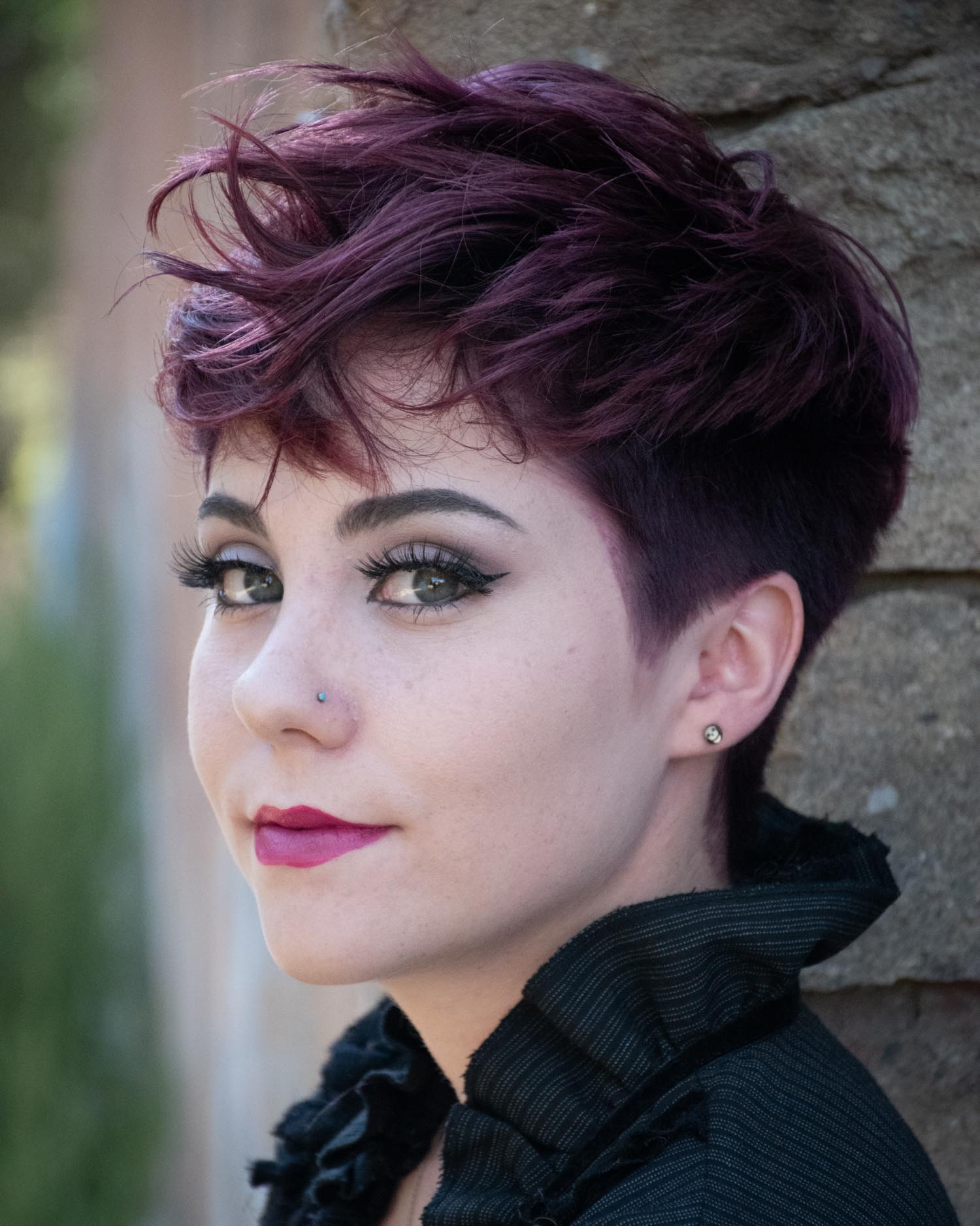 Woman with a textured, choppy pixie cut in deep burgundy.