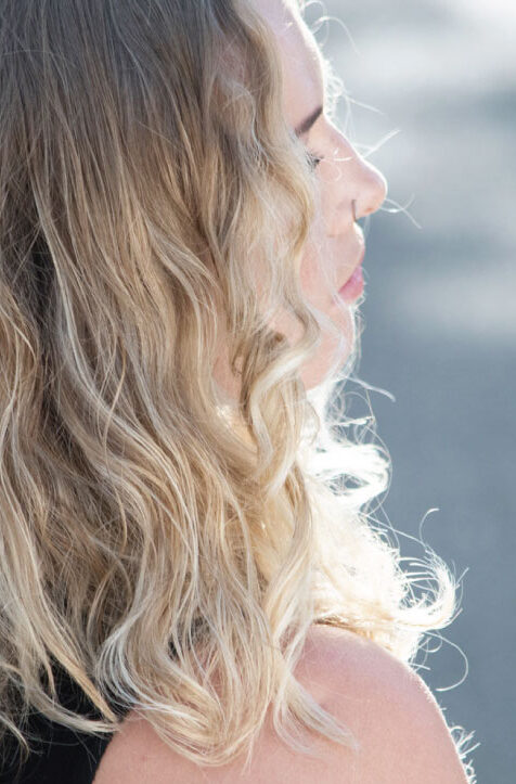 Profile view of a woman with long, wavy blonde hair highlighted by sunlight