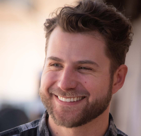 Man with a stylish, voluminous wavy hairstyle, smiling outdoors