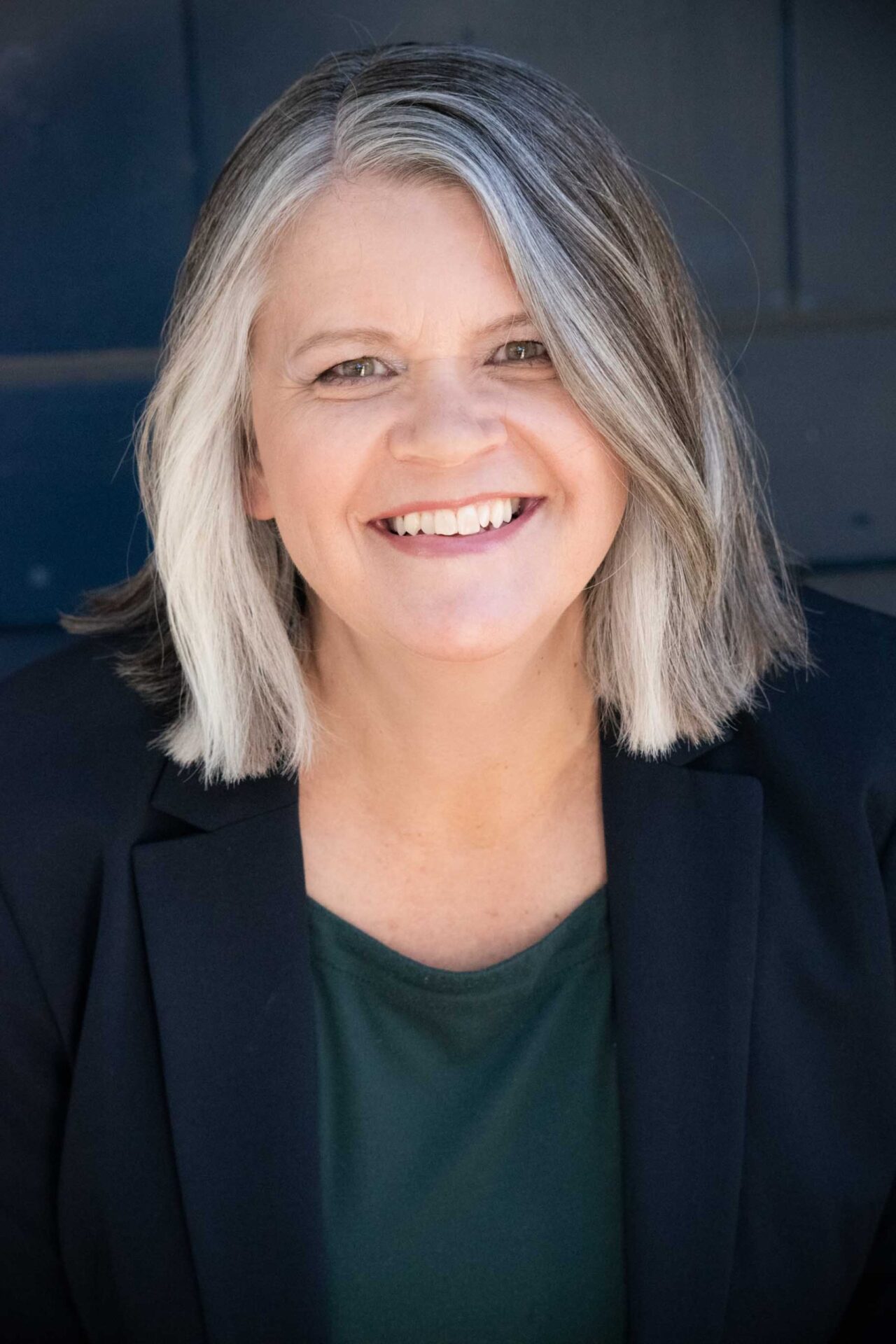 Woman with a stylish shoulder-length bob cut in salt and pepper grey.
