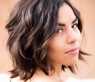 Woman with a textured, shoulder-length lob (long bob) featuring soft waves and subtle highlights