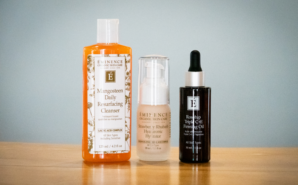 Three Eminence Organic Skin Care products displayed: Mangosteen Daily Resurfacing Cleanser, Strawberry Rhubarb Hyaluronic Hydrator, and Rosehip Triple C+E Firming Oil